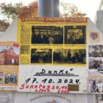 Das Foto zeigt ein Schild mit einer Collage. Sie Auf ihr sind Fotos des Gebäudes Gaswerkehaus in Uetersen zu sehen. Hier ist das Heimatmuseum untergebracht. Dazu gibt es einen Ausschnitte aus der Zeitung Uetersener Nachrichten. In dem Artikel wird über den Ortstermin berichtet, bei dem über den Standort der neuen 3-Feld-Halle beraten wurde. Der Titel des Artikels lässt vermuten, dass das Gebäude nicht abgerissen werden muss. Darunter ist noch ein Papier aufgeklebt mit den Worten "Danke - 17.10.2024" und "Sonntag, 20.10.2024 offen". Im Hintergrund sind die herbstlich gefärbten Blätter eines Baumes zu erkennen.